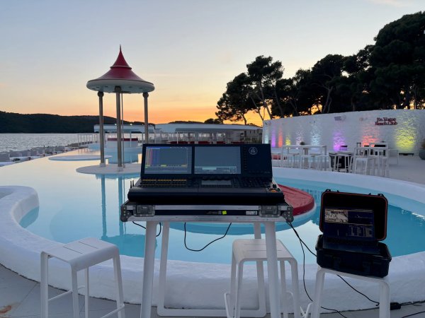 Sunset lighting design setup beside an infinity pool at a beach club on the Croatian coast, with a lighting control console and colored architectural wall lighting.
